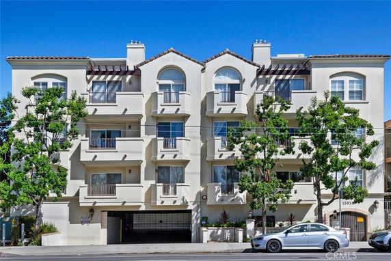 Front view of a multi-story residential building with balconies and a gated entry.