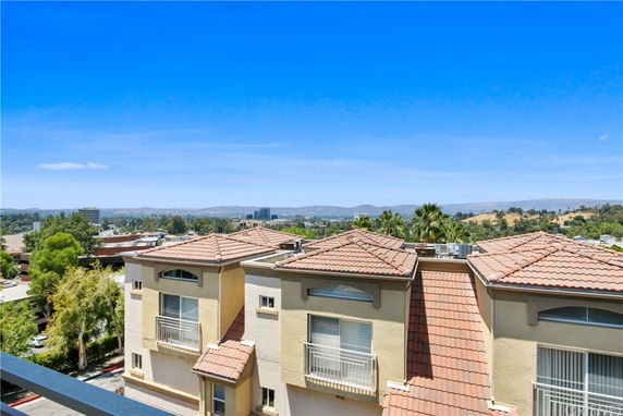 Panoramic view of a residential complex with surrounding landscape and hills in the background.