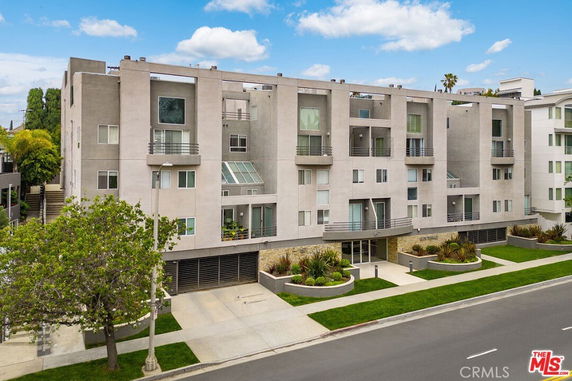 Front view of a multi-story apartment building with balconies and modern design.