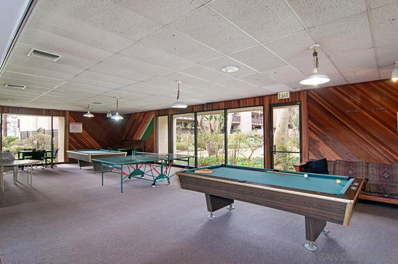 Room with billiards and table tennis tables in a recreational area.