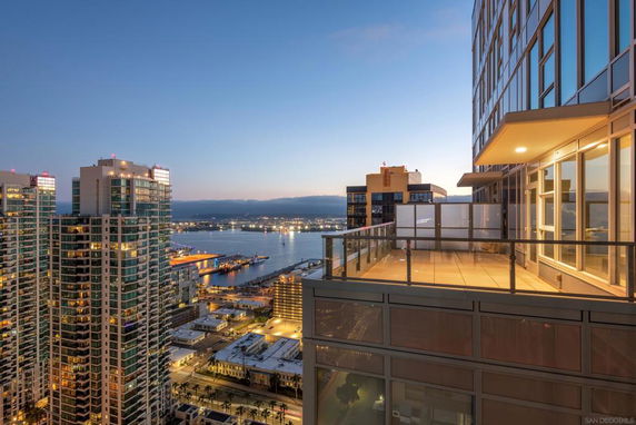 Panoramic view from a high-rise building overlooking a city and waterfront at dusk.