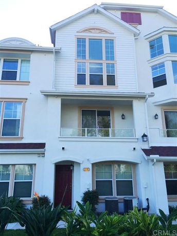 Front view of a multi-story townhome with large windows and a balcony.