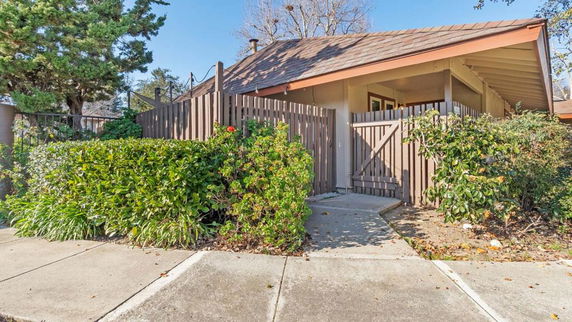 Front view of a single-story house with a wooden fence and sloped roof.