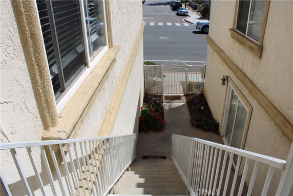 Staircase leading down to a gated entrance with a view of the street in front of a building.