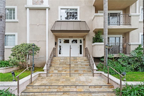 Front view of a multi-story residential building with stairs leading to the entrance.