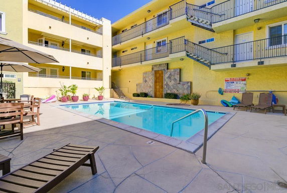 Outdoor area with swimming pool surrounded by a multi-story residential building.