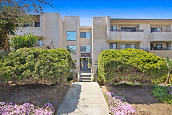 Front view of a multi-story apartment building with balconies and a central entrance.
