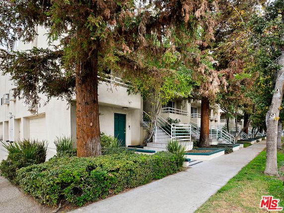 Front view of a multi-story building with staircases and greenery.