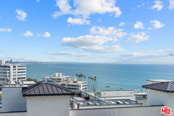 Panoramic view from a building overlooking the ocean and nearby structures.