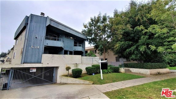 Front view of a multi-story building with balconies and gated entrance.