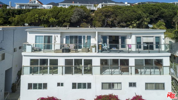 Front view of a multi-story house with glass balconies and large windows.