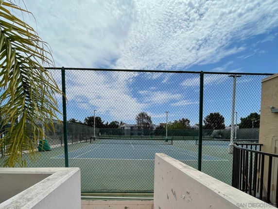 View of an outdoor tennis court surrounded by a fence.