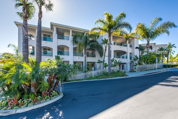 Front view of a multi-story building with balconies and palm trees.