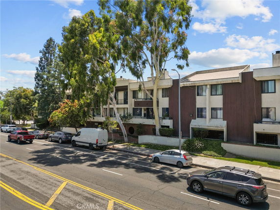 Front view of a three-story apartment building with a brown and white exterior.