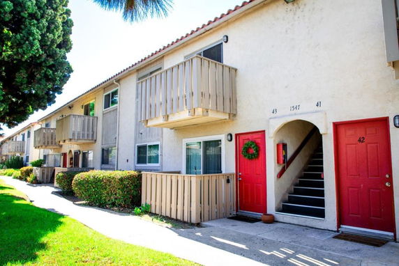 Front view of a two-story apartment complex with red doors and small balconies.