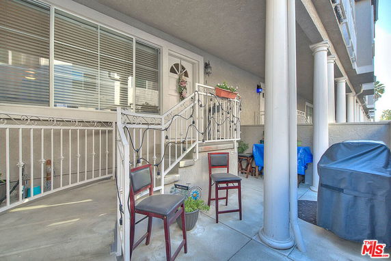 Front view of a residential building with a small porch, columns, and decorative railing.