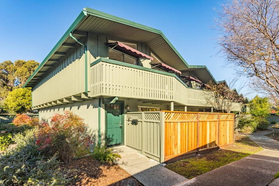 Front view of a two-story house with a wooden fence and balcony.