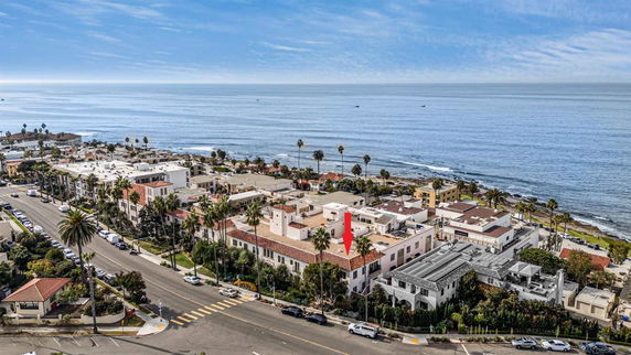 Aerial view of a coastal neighborhood with houses and a road near the ocean.