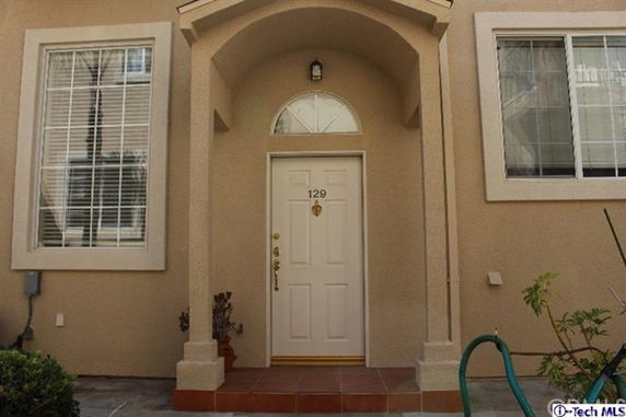 Front view of a house with an arched entryway and a white door.