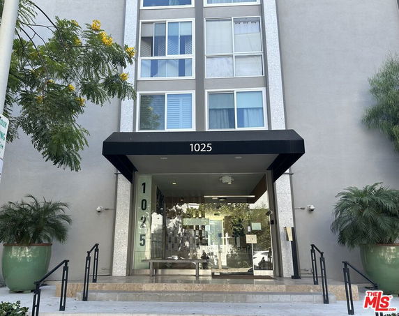 Front view of a multi-story building entrance with glass doors and the number 1025 displayed above.