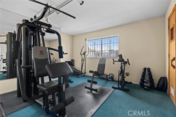 Room with various gym equipment including a weight machine and exercise bikes.