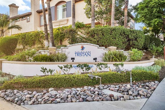 Front view of a multi-story building with landscaped garden and a prominent entrance sign.