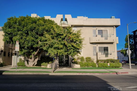 Front view of a three-story residential building with balconies and glass block windows.