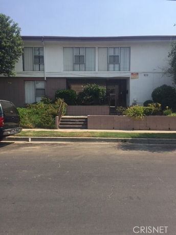 Front view of a two-story residential building with a central entrance and surrounding shrubs.
