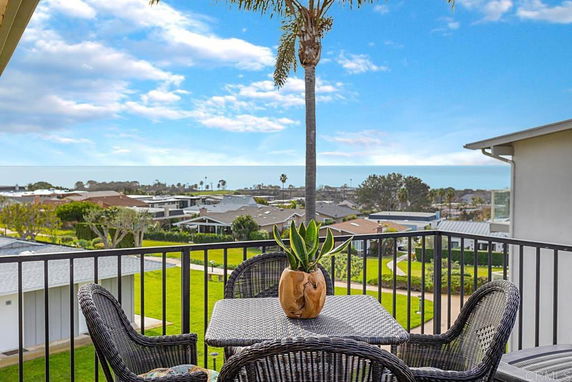 Balcony view overlooking a residential area with a distant ocean horizon.