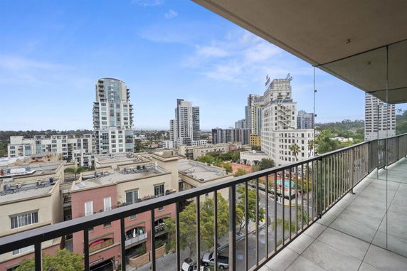 Panoramic view of a cityscape with high-rise buildings from a balcony.