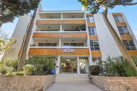 Front view of a multi-story apartment building with balconies and large glass windows.