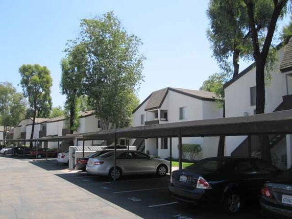 Outdoor parking area with multiple parked cars and adjacent residential buildings.