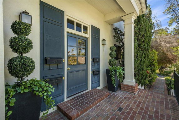 Front view of a house entrance with a dark blue door and decorative plants.