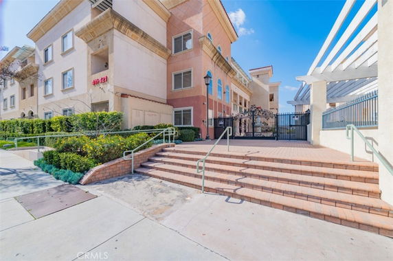 Front view of a multi-story residential building with gated entrance and steps.