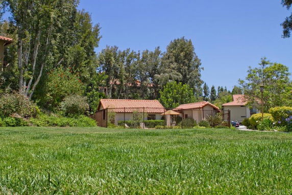 View of single-story buildings with red-tiled roofs surrounded by trees and greenery.