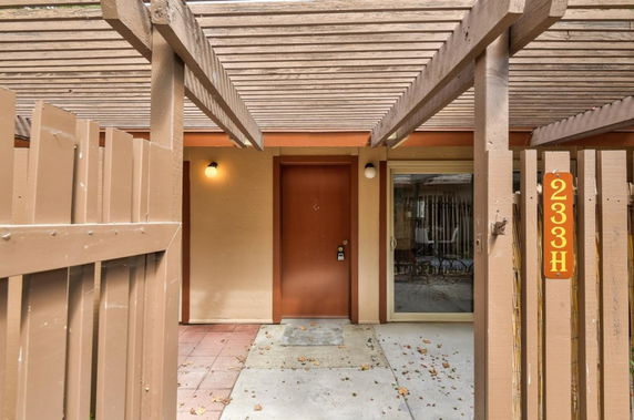 Front view of a building entrance with a light brown door and wooden framework.
