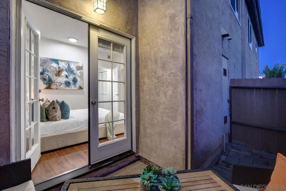 View from the patio showing a bedroom through glass doors and adjacent exterior wall of the building.