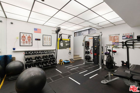 Indoor gym room with exercise equipment and anatomical posters on the wall.