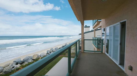 View from a balcony overlooking the ocean and beach.