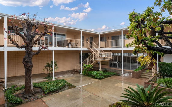Front view of a two-story apartment building with an external staircase and balcony walkways.