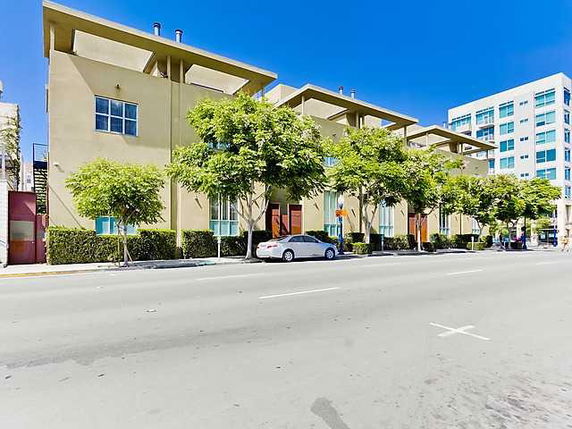 Front view of a multi-story building with large windows and trees lining the street.