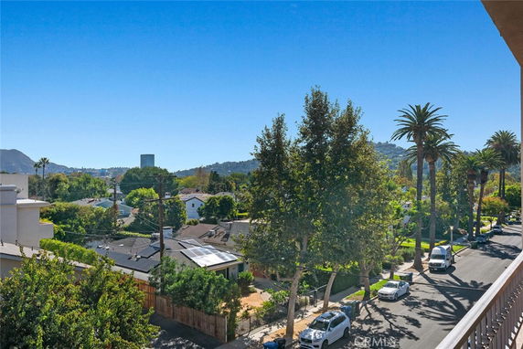 Panoramic view of a neighborhood with trees and distant hills.