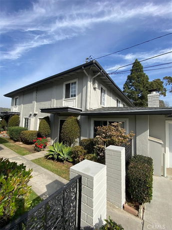 Front view of a two-story house with a chimney and well-maintained shrubs.