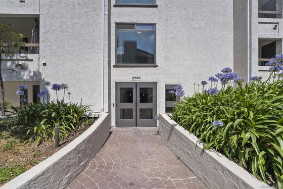 Front view of a building entrance with double doors and flower beds.
