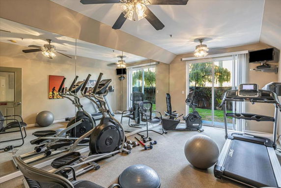 Indoor gym with exercise equipment and mirrored wall.
