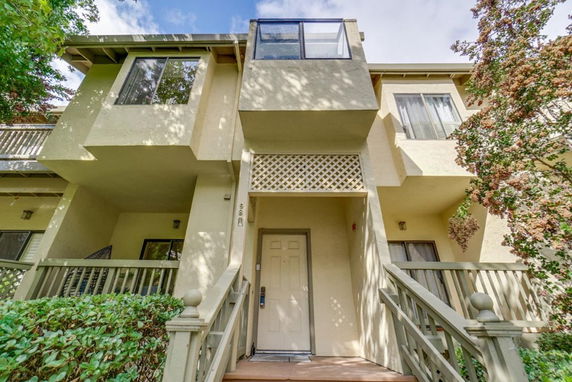 Front view of a multi-story house with a balcony and stairs leading to the entrance.