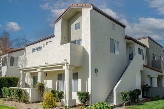 Front view of a two-story white house with a staircase and balcony.