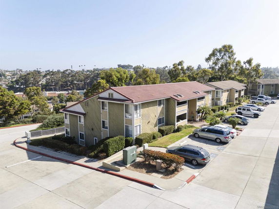 Parking area next to a multi-story apartment building with a sloped roof.