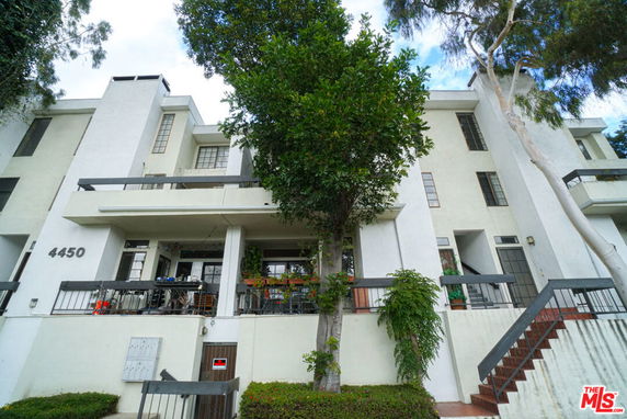 Front view of a multi-story residential building with balconies and a staircase.