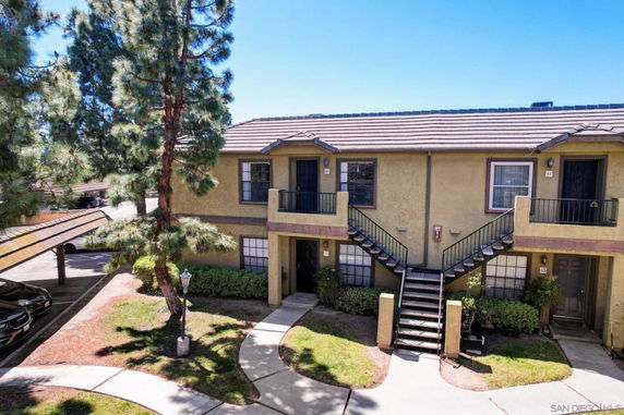 Front view of a two-story residential building with external stairs leading to the upper level.